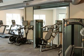 A gym with a variety of exercise equipment including treadmills, stationary bikes, and weight machines.